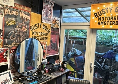 Interior of The Wolf Barber Shop in Amsterdam, NL, featuring retro motorcycle posters and decor.