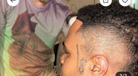 Barber at Payso Cuts in New York, New York, US giving a precise haircut to a client with intricate tattoos.