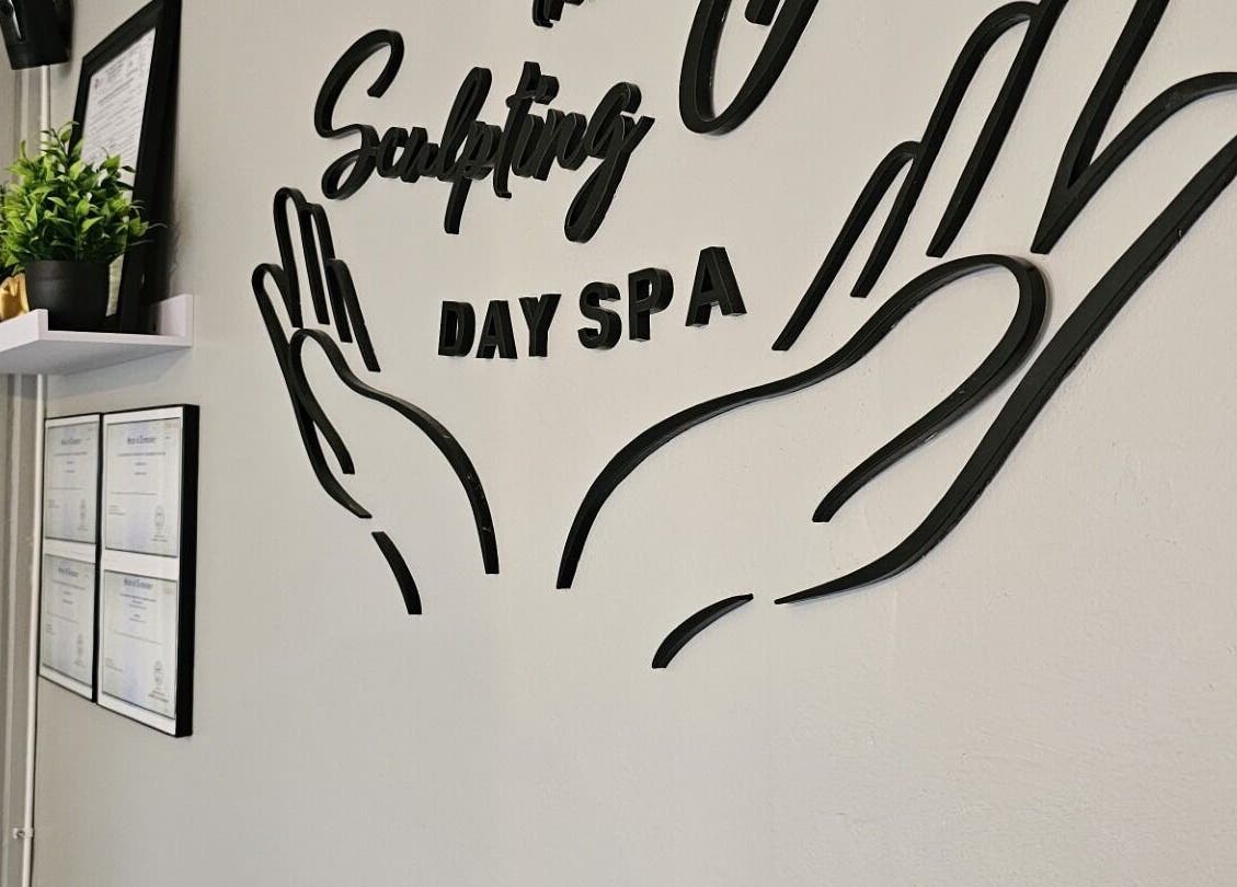 Decorative wall art at The Sculpting Art Day Spa in Hendersonville, TN, US. Certificates and plants adorn the shelf.