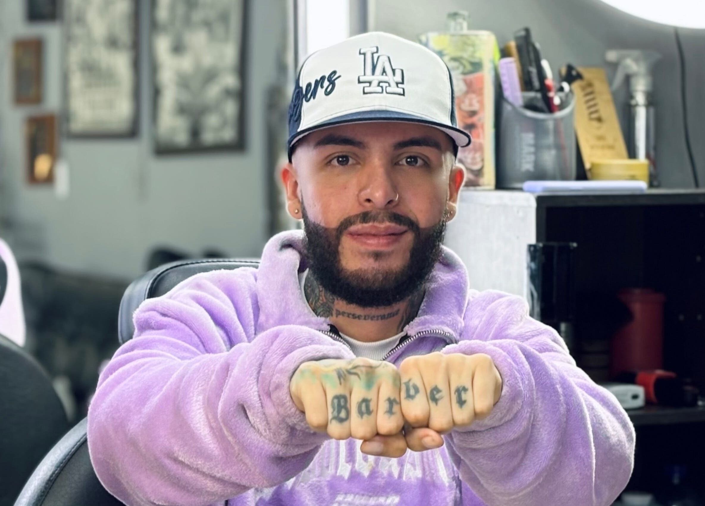 Hombre en Sebastyile Barber en Marinilla, Antioquia, CO mostrando tatuaje 'Barber' en sus nudillos.