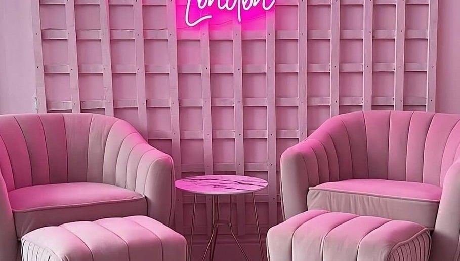 Chic pink lounge at Facecard_ap, Purley, England, GB. Cozy seating and neon sign offer elegance and warmth.