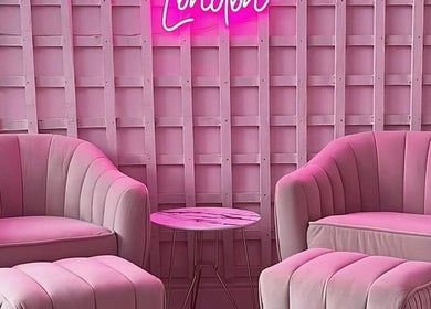 Chic pink lounge at Facecard_ap, Purley, England, GB. Cozy seating and neon sign offer elegance and warmth.