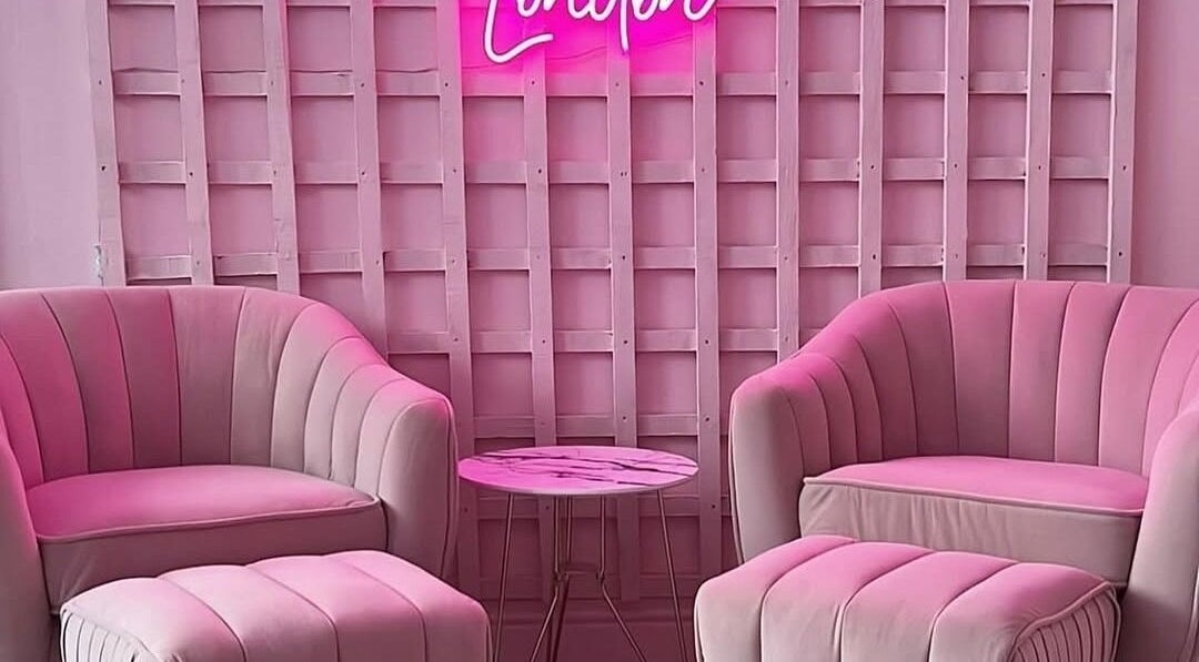 Chic pink lounge at Facecard_ap, Purley, England, GB. Cozy seating and neon sign offer elegance and warmth.