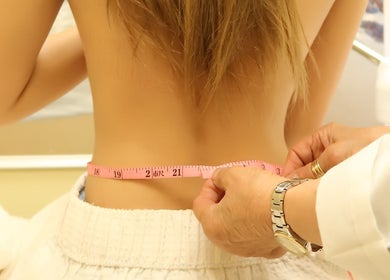 Professional measuring a client's waist at Sky Spa Laser, Forest Hills, New York, US, emphasizing precision care.