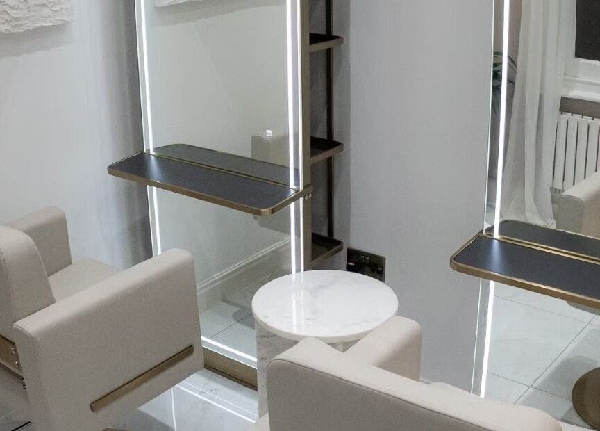 Elegant salon chairs and mirror at Tresses By Em, GB. Modern design with neutral tones and stylish lighting.