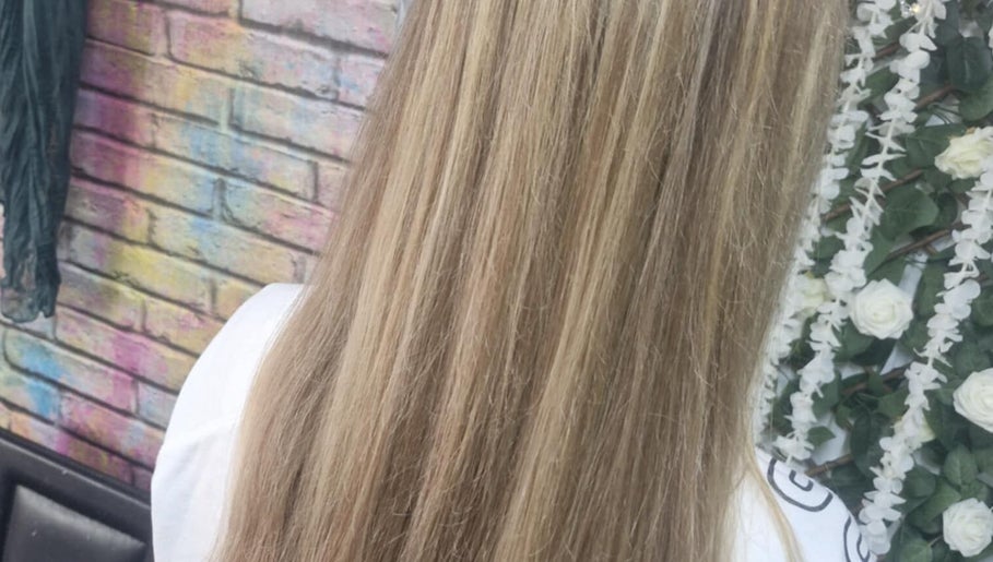 Elegant long blonde hair against a floral backdrop at Roots & Rebel, Ellesmere Port, England, GB.