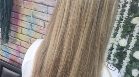 Elegant long blonde hair against a floral backdrop at Roots & Rebel, Ellesmere Port, England, GB.