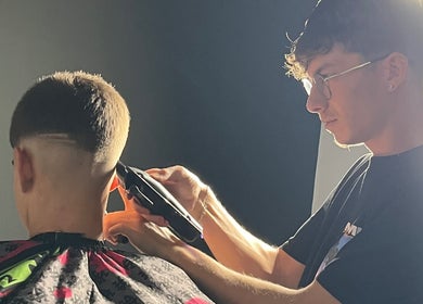 Barbero de SvBarbers en Burguillos, Andalucía, ES realizando corte preciso bajo iluminación perfecta.