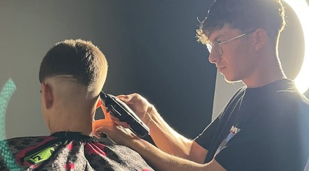Barbero de SvBarbers en Burguillos, Andalucía, ES realizando corte preciso bajo iluminación perfecta.