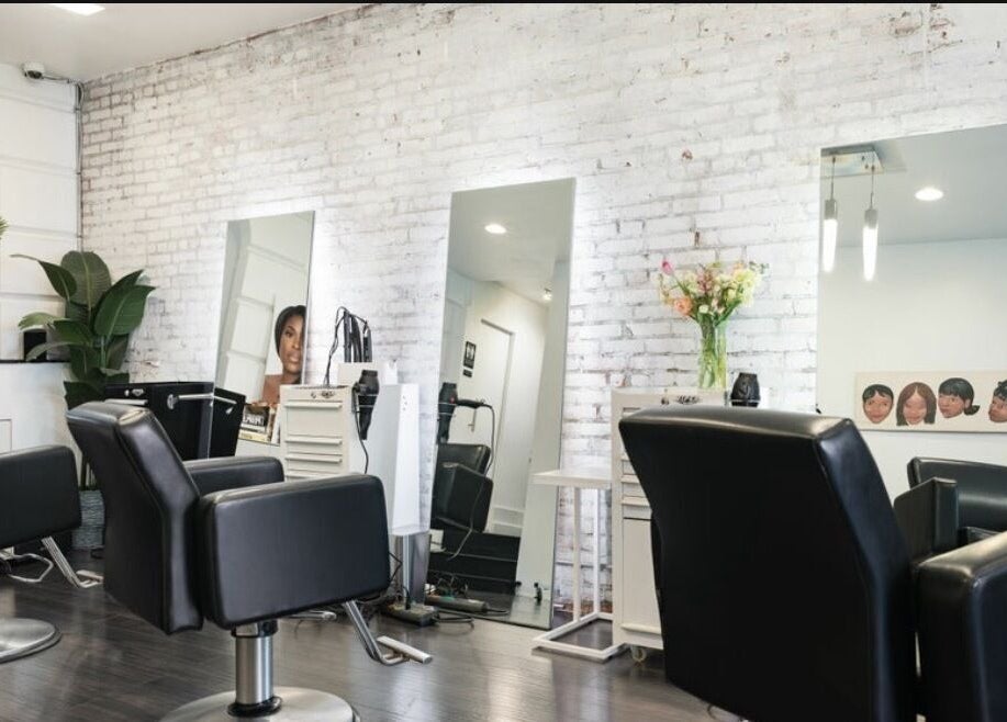 Modern interior of Chic Luxury Hair Studio in New York, New York, US with styling chairs and mirrors.