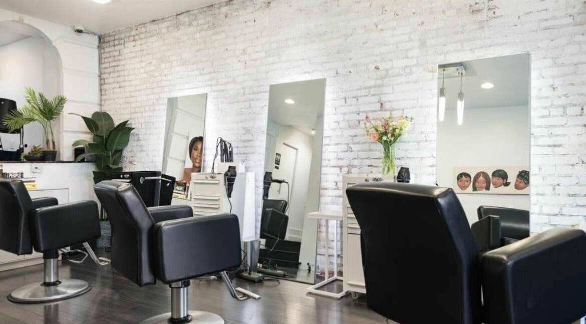 Modern interior of Chic Luxury Hair Studio in New York, New York, US with styling chairs and mirrors.