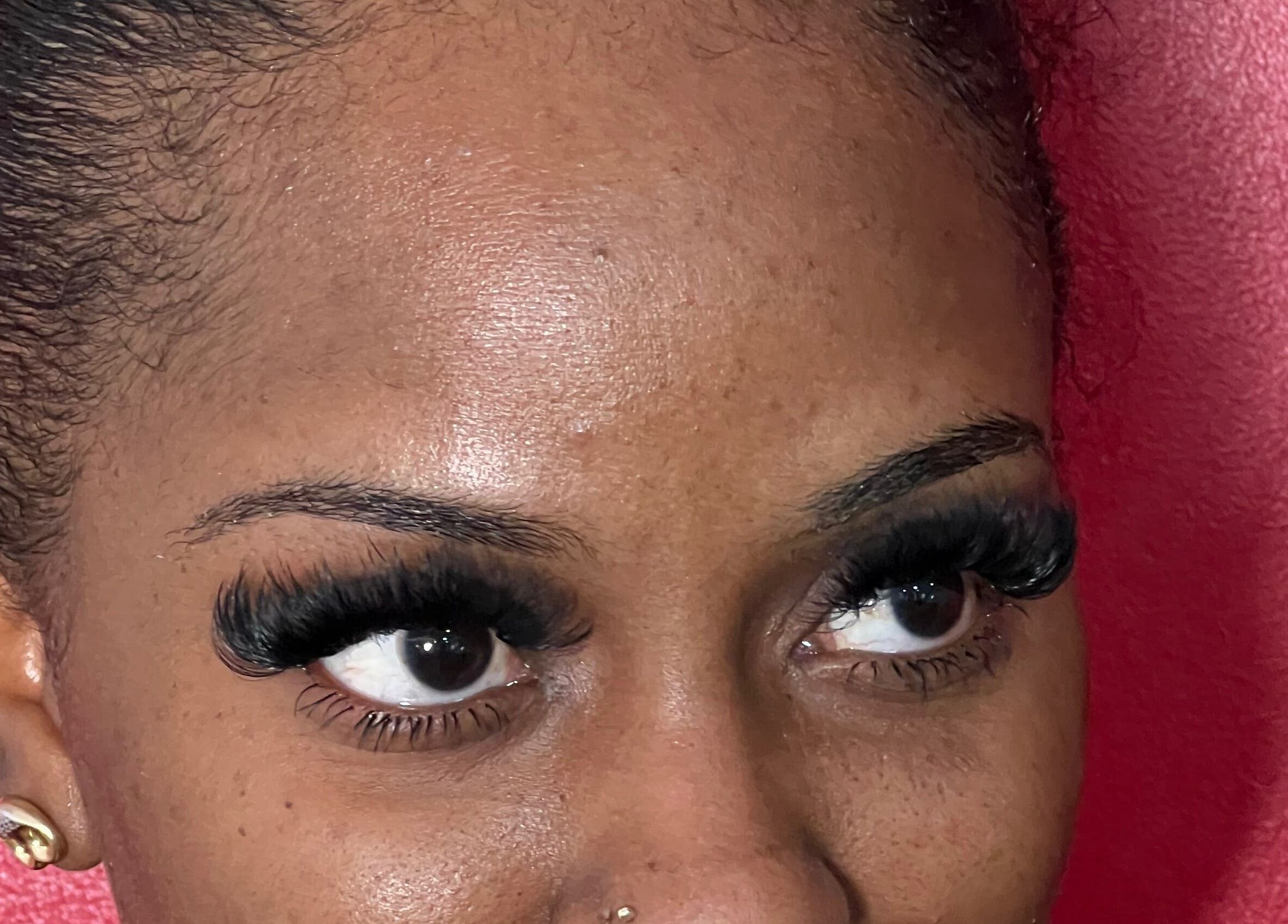 Close-up of a woman's elegant lashes at Poised Beauty, Sint Maarten, SX against a pink backdrop.