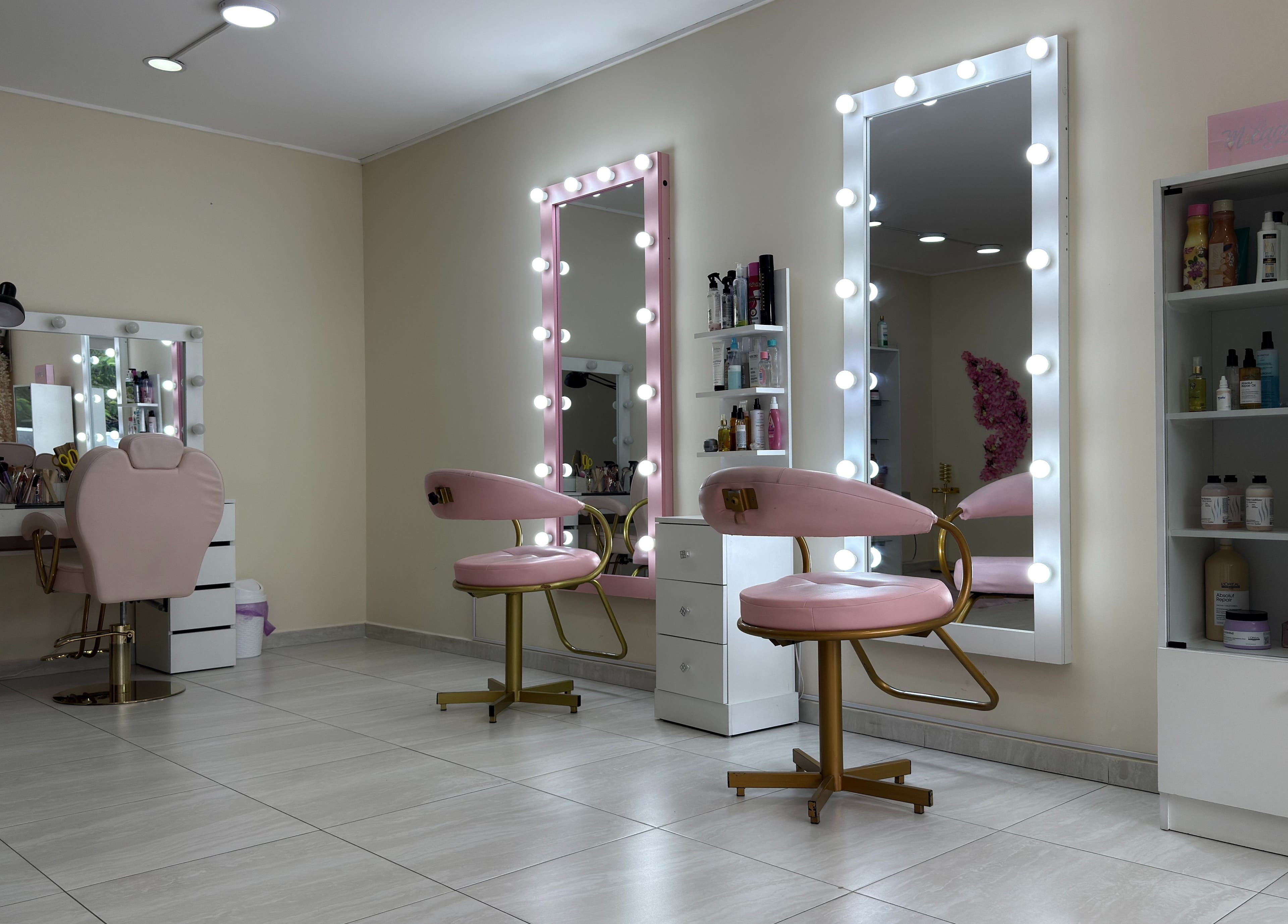 Interior elegante de ByLove Spa en Santa Cruz De La Sierra, con sillas rosas y espejos iluminados.