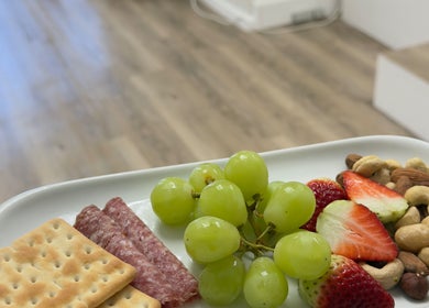 Assorted snacks at Elite Spa and Beauty, Cape Town, Western Cape, ZA, featuring fruit, nuts, and crackers.