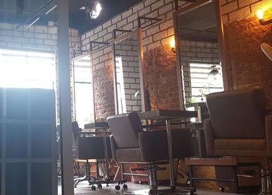Interior moderno del salón 'The Fashion Victim' en Ciudad De México, MX, con sillas elegantes y decoración de ladrillo.