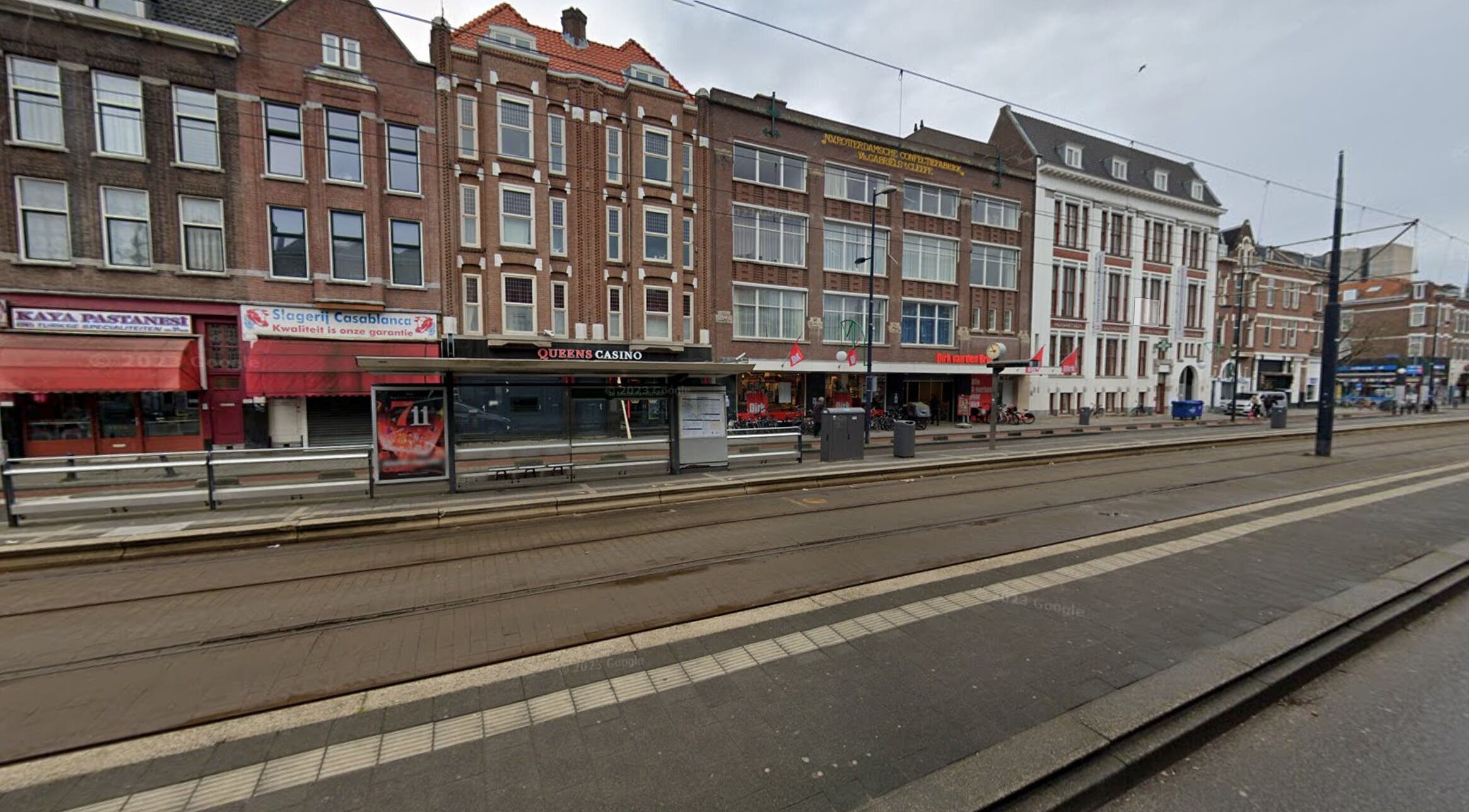 Street view of CarlosKapperRotterdamWest's location in Rotterdam, Zuid-holland, NL with tram tracks and storefronts.