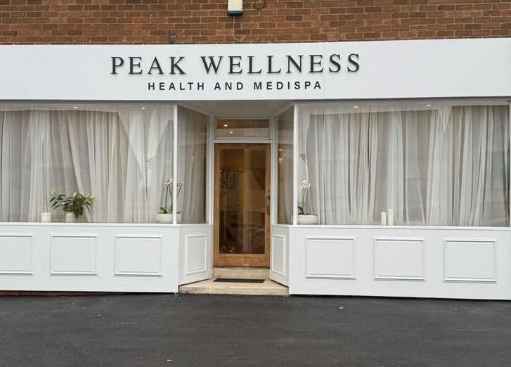 Entrance of Peak Wellness Health and Medispa in Dronfield, England, GB with white decor and potted plants.