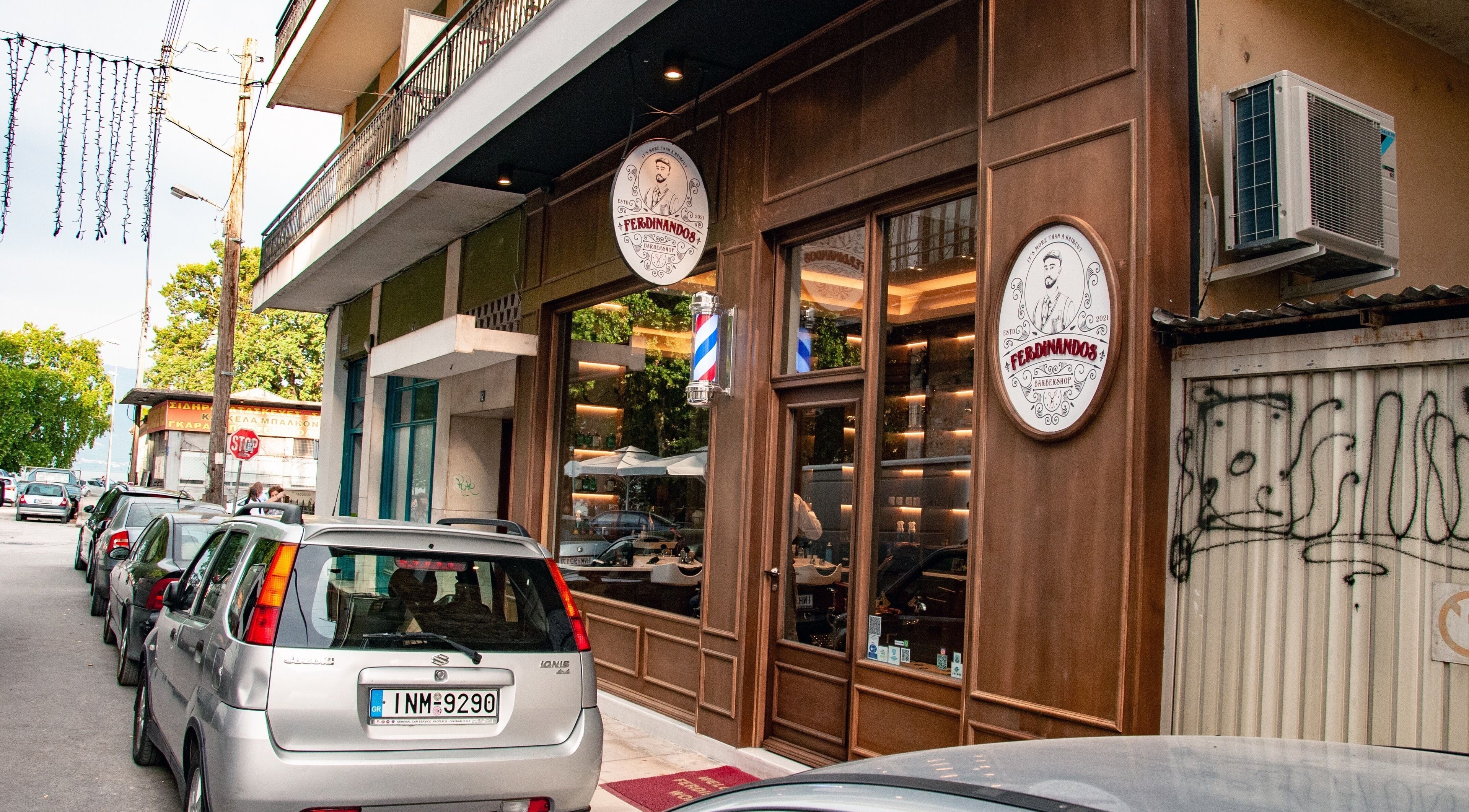 Εξωτερική όψη του Ferdinandos Barbershop στην Ιωάννινα, GR, με κομψή ξύλινη επένδυση και πινακίδα.