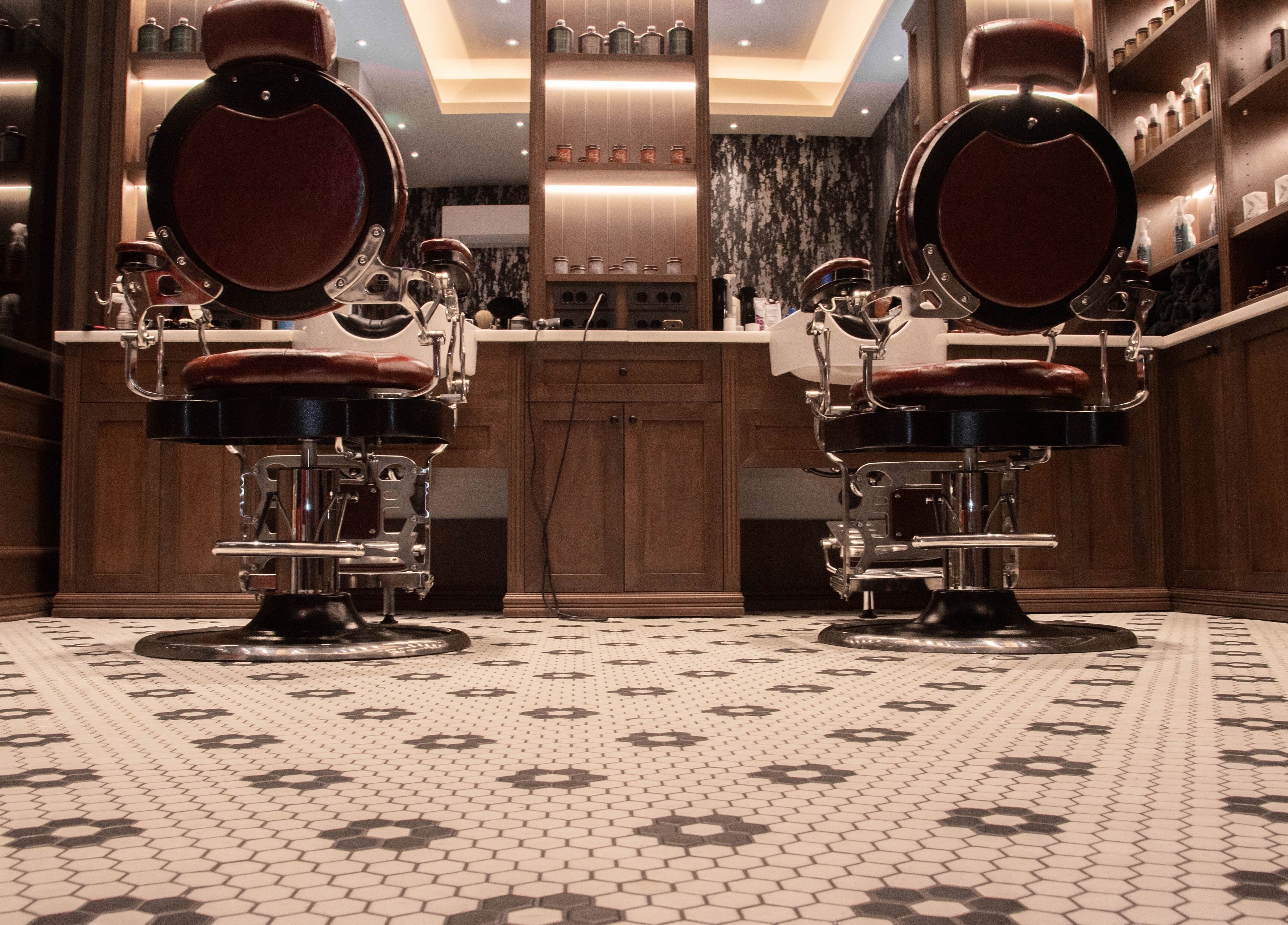 Δύο κλασικές καρέκλες κουρέα στο Ferdinandos Barbershop, Ιωάννινα, GR, με κομψή διακόσμηση.