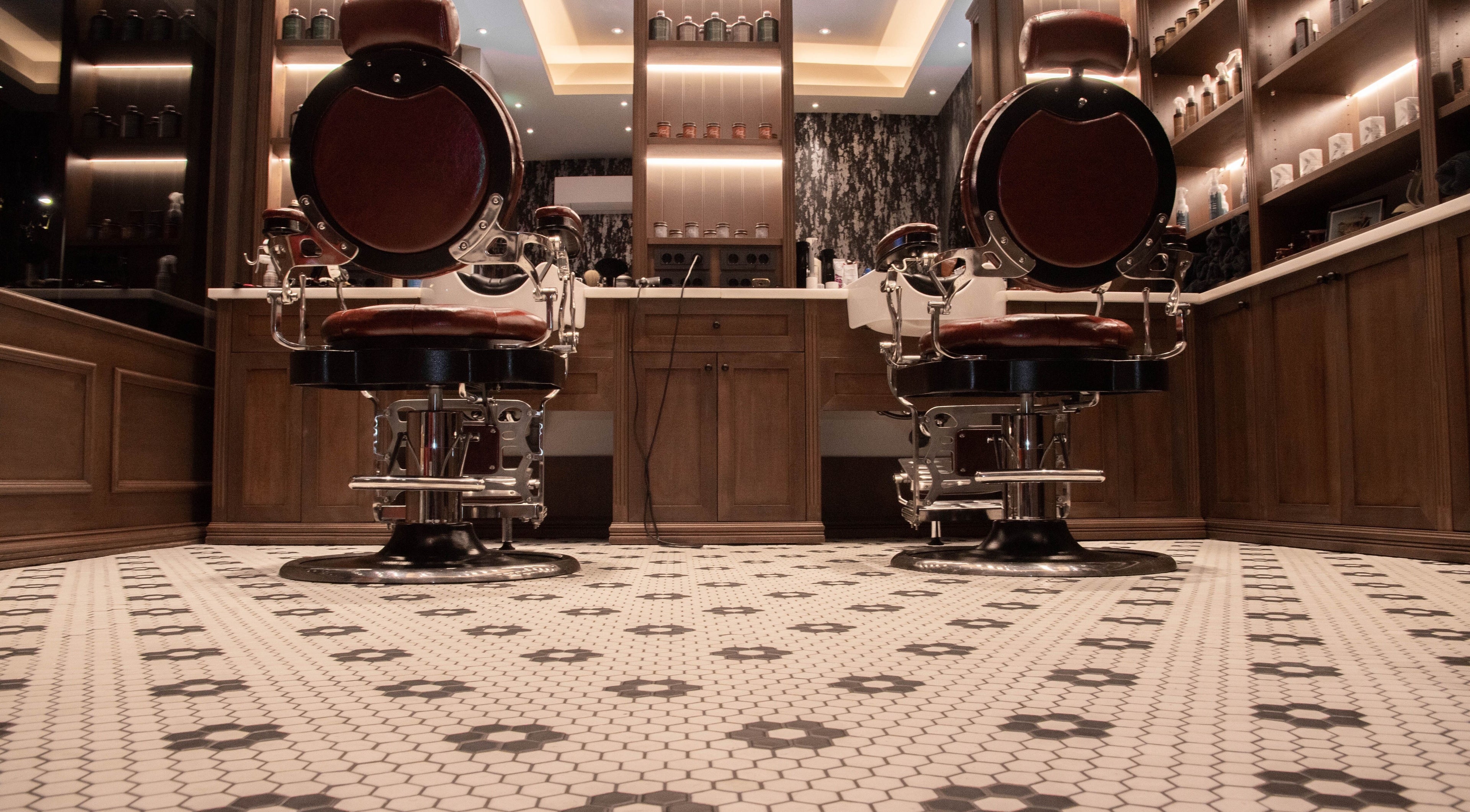 Δύο κλασικές καρέκλες κουρέα στο Ferdinandos Barbershop, Ιωάννινα, GR, με κομψή διακόσμηση.