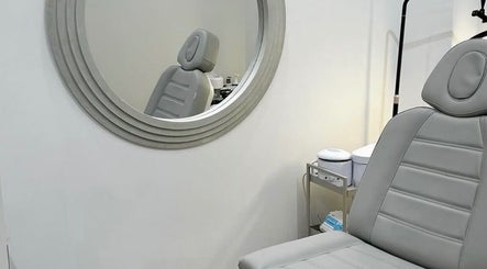 Modern treatment room with gray chair and round mirror at Reset Beauty, London, England, GB.