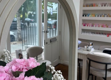 Elegant view inside Reset Beauty, London, England, GB, showcasing flowers, nail polish display, and cozy seating.