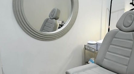 Calm and stylish treatment room at Reset Beauty, London, England, GB, featuring a plush chair and round mirror.