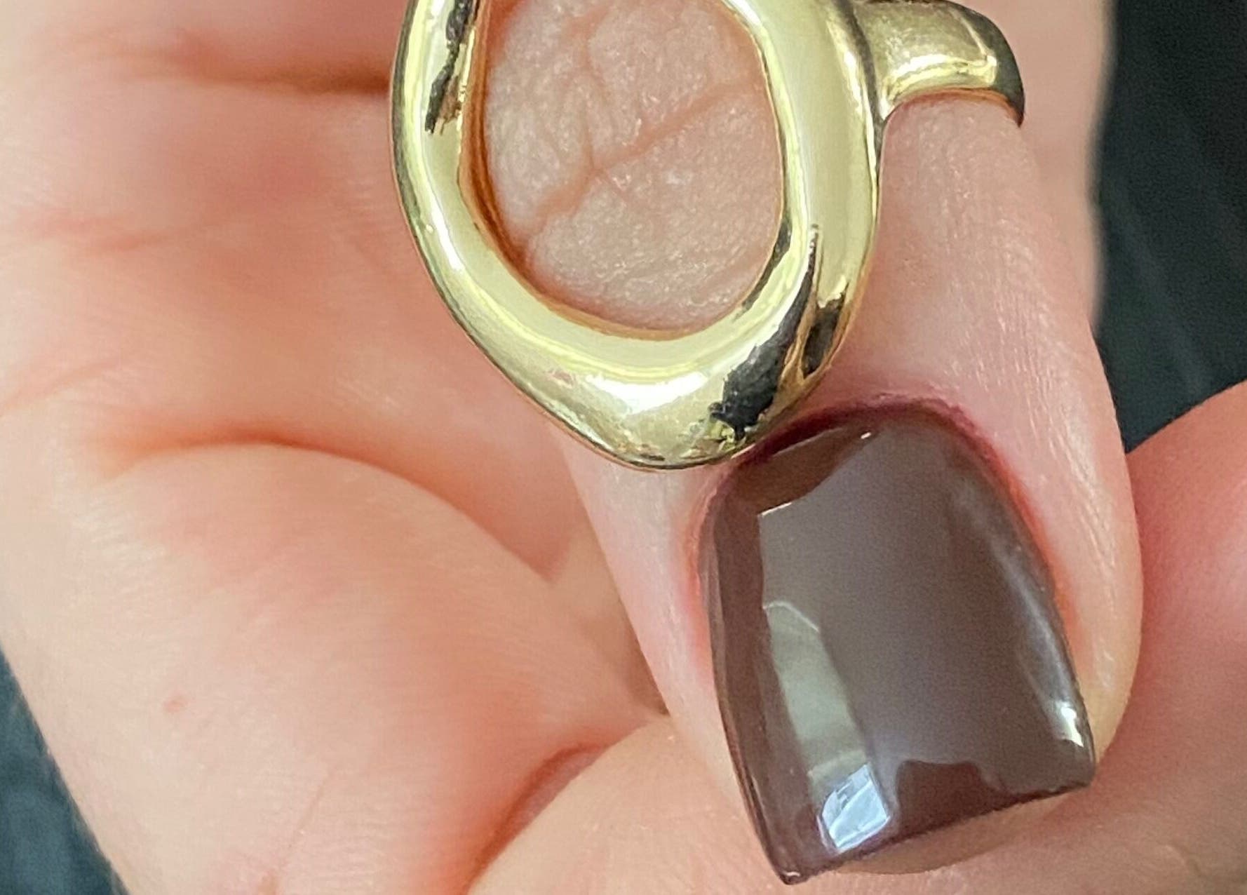 Mano con anillo dorado y uña marrón en Yaitorres.Nails, Cali, Valle Del Cauca, CO.