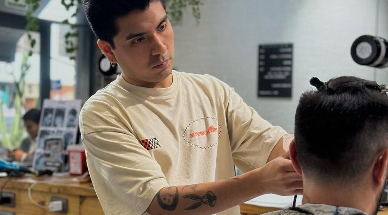 Barbero concentrado trabajando en corte de cabello en Groomed Hair, Miraflores, Provincia De Lima, PE.