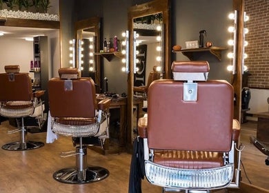 Modern styling chairs at Clean Cut salon in Budapest, Magyar, HU, featuring sleek mirrors and ambient lighting.