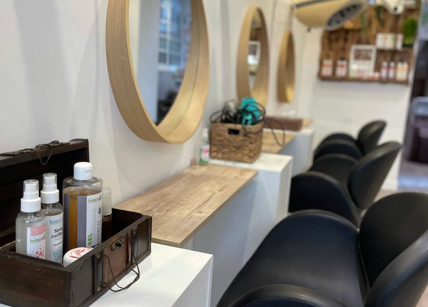 Intérieur élégant du salon Biocoiff Vincennes à Vincennes, Île-de-France, FR avec miroirs circulaires et produits.