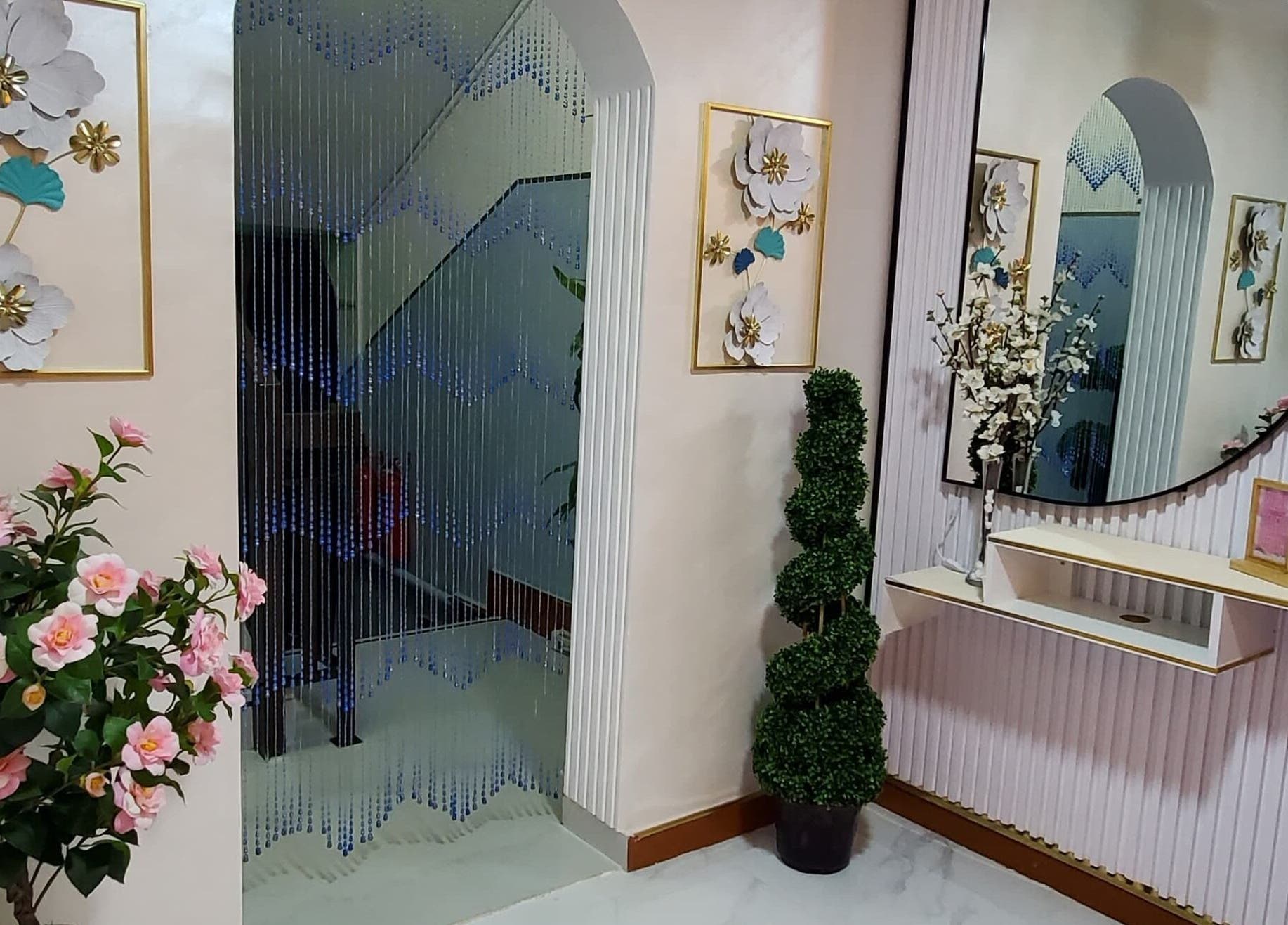 Elegant entrance at Modiva Spa and Wellness, Al Ain, Abu Dhabi, AE featuring floral decor and a large mirror.