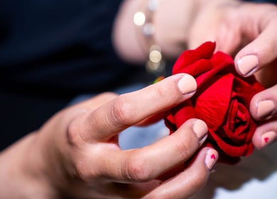 Manicured hands with a red rose at NailsbyAjita, Northwood, England, GB. Perfect nail artistry display.