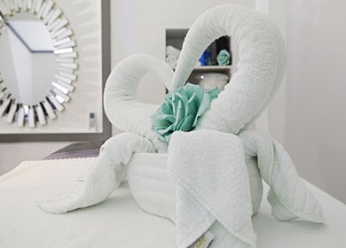 Ornately folded towels with flower at Garra Beauty Spa in Simpsonbay, SX. Relaxing ambiance reflected by mirror.