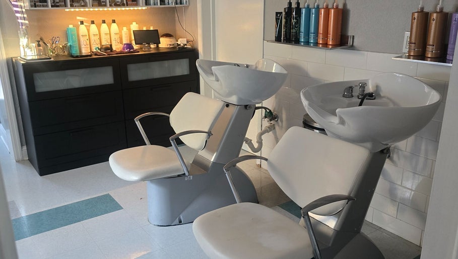 Stylish wash station at Beach Hair Affair in St. Petersburg, Florida, US featuring modern white chairs and shelves.