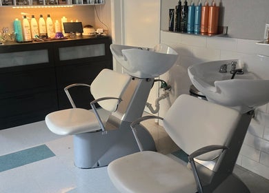 Stylish wash station at Beach Hair Affair in St. Petersburg, Florida, US featuring modern white chairs and shelves.