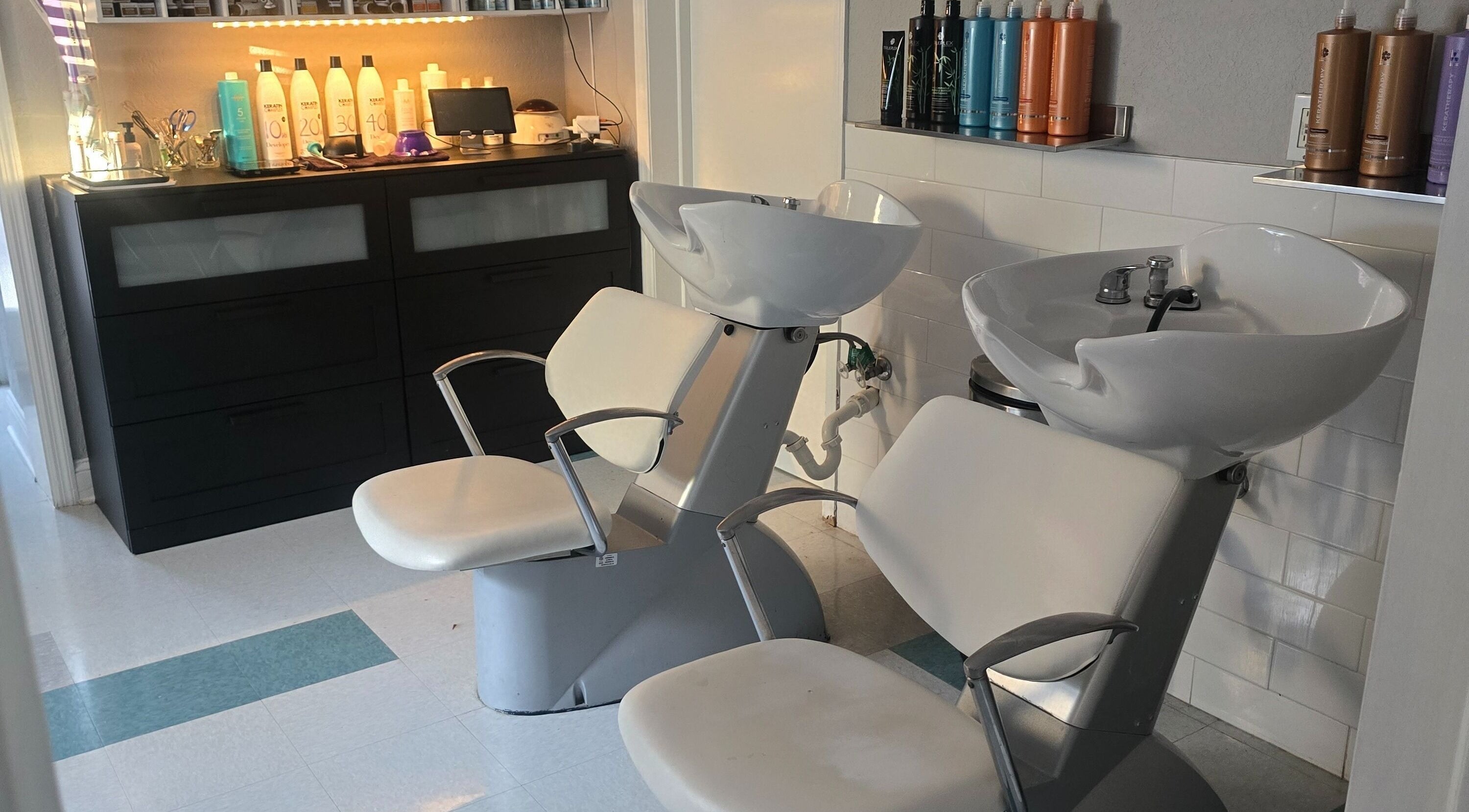 Stylish wash station at Beach Hair Affair in St. Petersburg, Florida, US featuring modern white chairs and shelves.