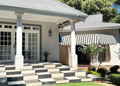 Entrance of Cateon Luxury, Pretoria, Gauteng, ZA, featuring grand columns and lush greenery.