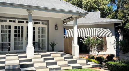Entrance of Cateon Luxury, Pretoria, Gauteng, ZA, featuring grand columns and lush greenery.