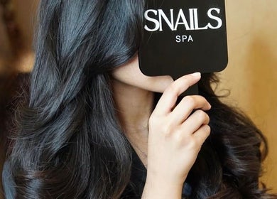 Elegant woman with long hair at Snails, Riyadh, Riyadh Province, SA, holding Snails branded mirror.