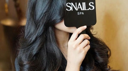 Elegant woman with long hair at Snails, Riyadh, Riyadh Province, SA, holding Snails branded mirror.
