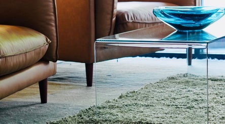 Stylish seating area at Jarod.hair, Surry Hills, New South Wales, AU with leather chairs and a glass table.