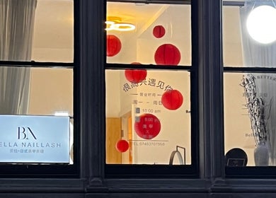 Bella Naillash window view with a stylish sign and red lanterns, showcasing elegance in Manchester, England, GB.