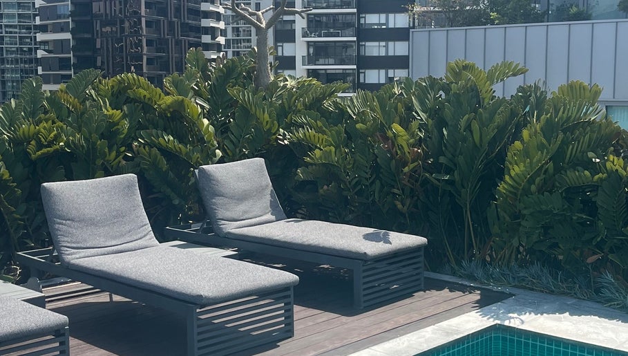 Relaxing lounge chairs by the pool at Clarkie Station, Milton, Queensland, AU, surrounded by lush greenery.