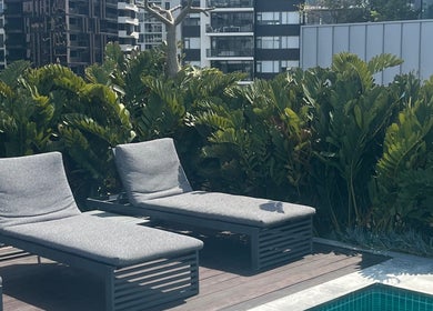 Relaxing lounge chairs by the pool at Clarkie Station, Milton, Queensland, AU, surrounded by lush greenery.