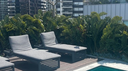 Relaxing lounge chairs by the pool at Clarkie Station, Milton, Queensland, AU, surrounded by lush greenery.