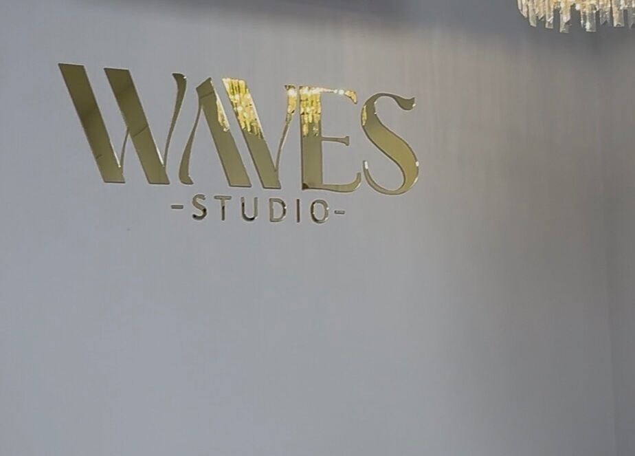 Logo Waves Studio na ścianie w Andrychów, Województwo Małopolskie, PL z eleganckim oświetleniem.