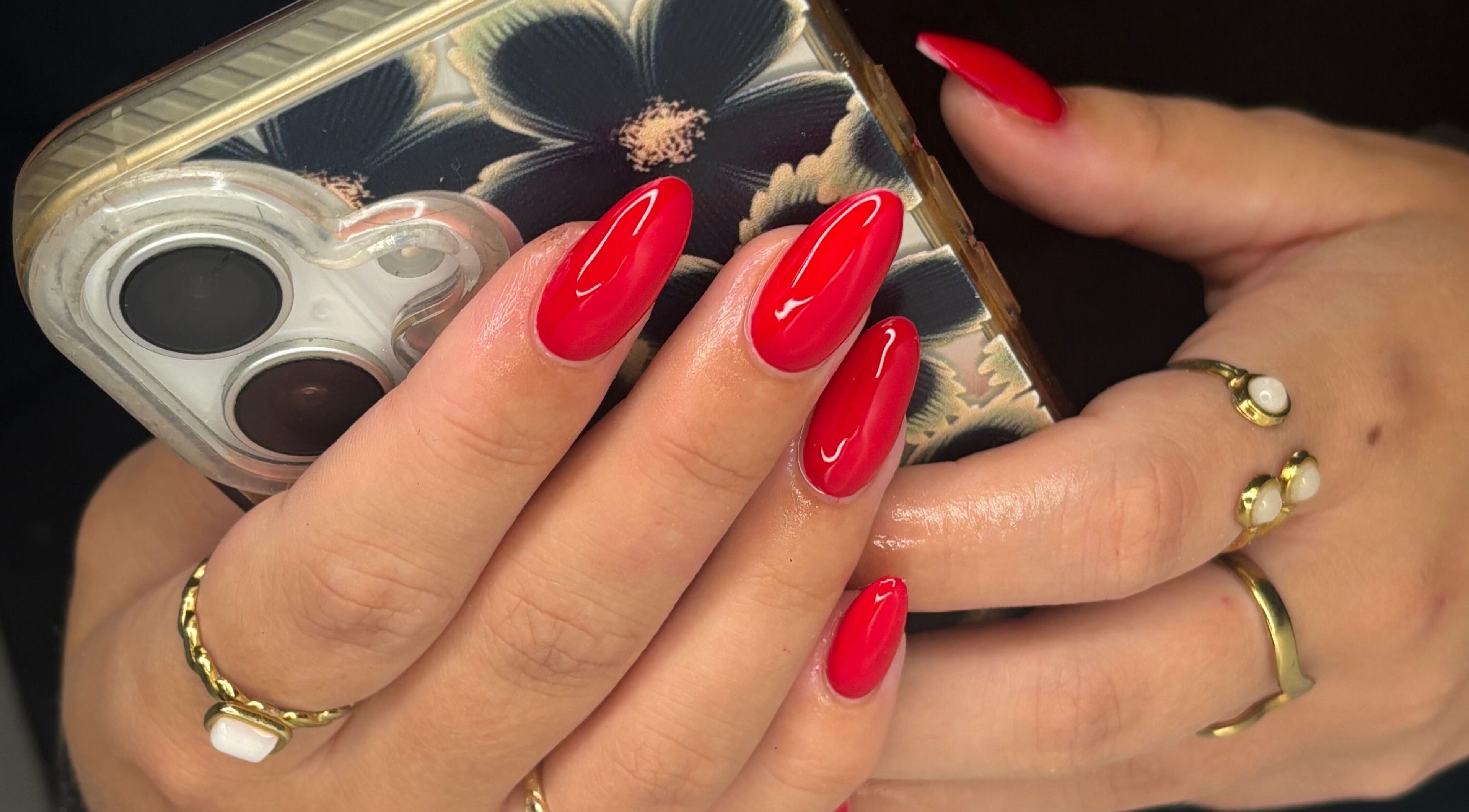 Vibrant red nails at Saunders Beauty | READING, Reading, England, GB. Elegantly manicured hands hold a phone.