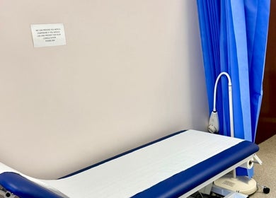Treatment room at Shannaz Aesthetics, Luton, England, GB, featuring a professional examination bed and blue privacy curtains.