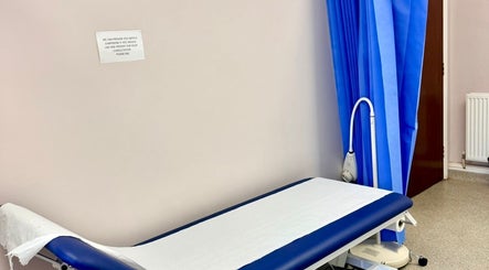 Treatment room at Shannaz Aesthetics, Luton, England, GB, featuring a professional examination bed and blue privacy curtains.